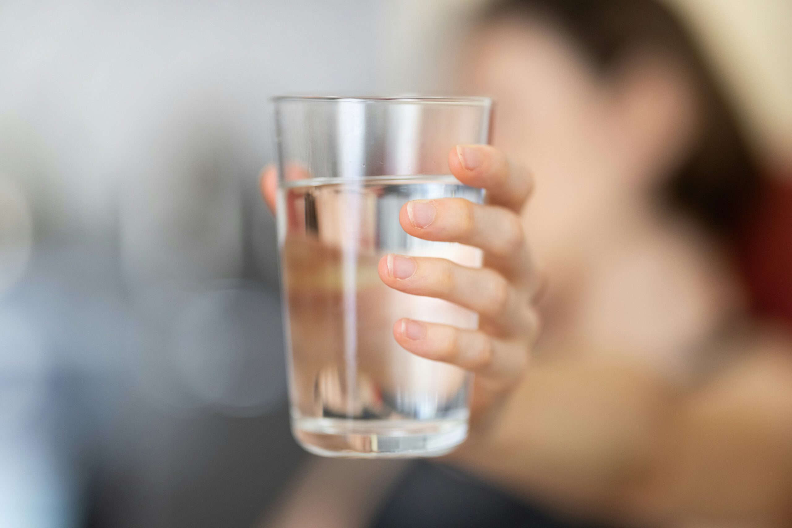 Glas mit Wasser in der Hand einer Frau