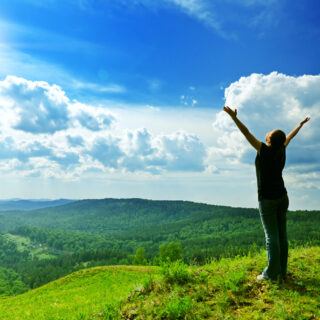 Frau auf einem grünen Berg als Symbol für Longevity und Gesundheit
