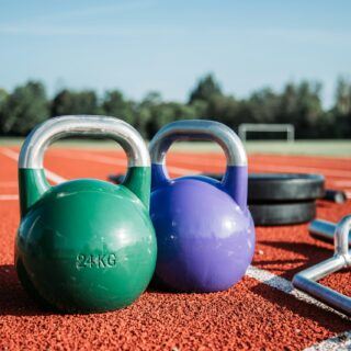 Bild mit Hantelnd und Fitnessgeräten auf einer Laufbahn